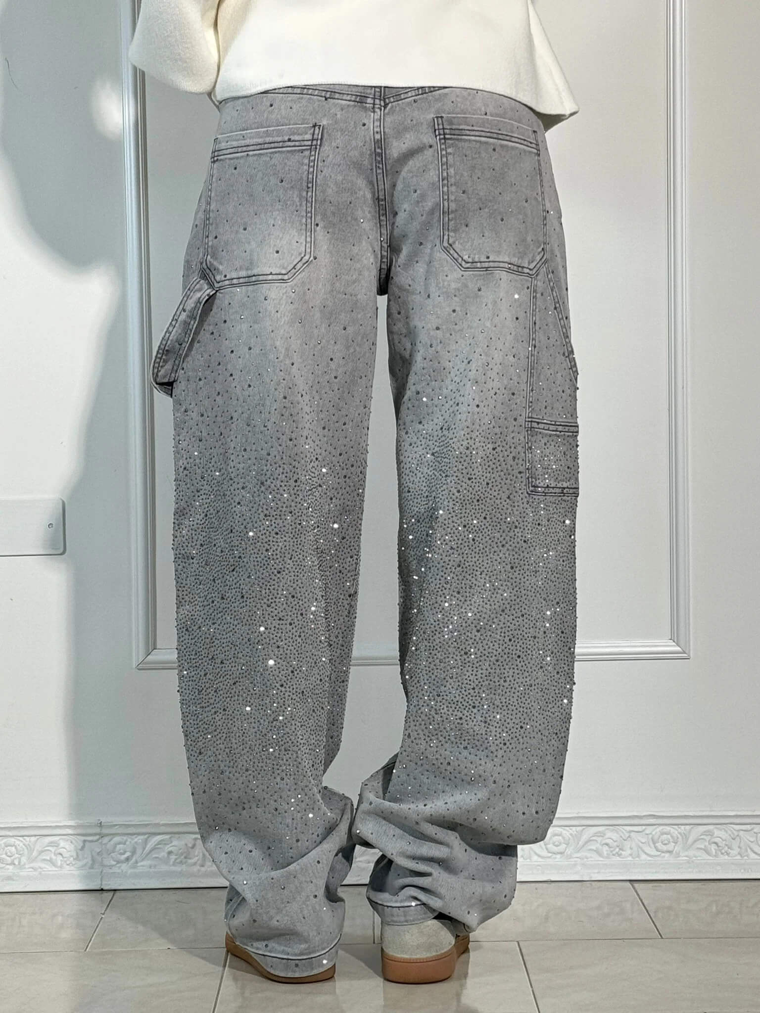 Jeans grigi da donna con strass, tasche posteriori e laterali, vestibilità ampia. Design moderno, ideale per look casual e alla moda.