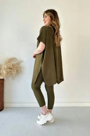 Donna in abbigliamento casual verde oliva, maglia oversize e leggings a coste, scarpe da ginnastica bianche. Sfondo neutro, stile moderno.
