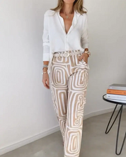 Camicia bianca elegante e pantaloni a fantasia geometrica beige, donna in posa. Moda femminile, abbigliamento casual chic, tendenze 2023.