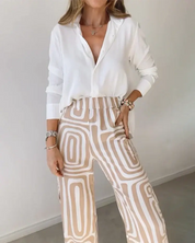Donna con camicia bianca e pantaloni a fantasia geometrica beige. Moda casual elegante, abbigliamento femminile trendy, outfit primaverile.