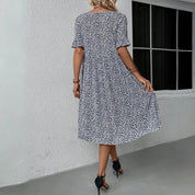 Abito estivo donna floreale bianco e nero, maniche corte, lunghezza al ginocchio, indossato da modella, sfondo bianco, moda casual elegante.