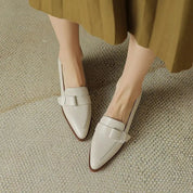 Scarpe mocassini donna in pelle bianca, design elegante con fiocco, su tappeto beige. Calzature moda femminile, stile casual chic.