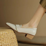 Scarpa da donna elegante in pelle bianca con tacco basso e dettaglio fiocco, su sfondo neutro. Scarpe moda femminile, calzature eleganti.