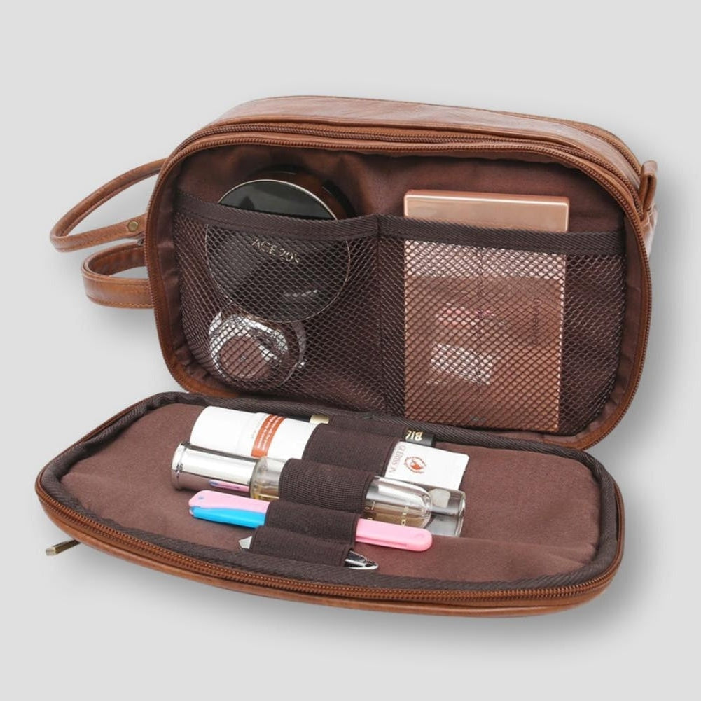 Astuccio da viaggio in pelle marrone aperto, con scomparti a rete contenenti cosmetici e accessori. Ideale per organizzare trucchi e prodotti di bellezza.