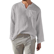 Camicia uomo bianca in lino con scollo a V e taschino, maniche lunghe, abbinata a pantaloni a righe. Stile casual estivo, moda maschile.