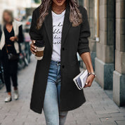 Donna con cappotto nero elegante, jeans, maglietta bianca, tiene caffè e borsa. Moda autunnale urbana, abbigliamento casual chic.