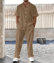 Completo estivo uomo marrone, camicia e pantaloni a righe, stile casual, abbinato a scarpe bianche. Look moderno e confortevole per la stagione calda.