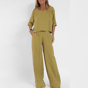 Donna con completo estivo verde oliva in lino, maniche corte e pantaloni larghi. Moda donna, abbigliamento casual, tessuto leggero e traspirante.