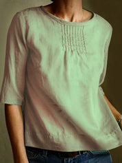 Maglietta donna in cotone verde chiaro, maniche a tre quarti, scollo rotondo, dettagli plissettati sul petto. Moda casual, abbigliamento estivo.