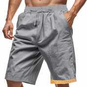 Pantaloncini sportivi grigi da uomo con tasche, elastico in vita e bordo decorativo arancione. Ideali per fitness e attività all'aperto.