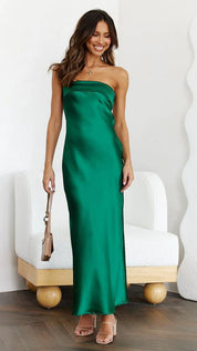 Abito lungo verde smeraldo senza spalline, elegante e lucido, indossato da una donna sorridente. Perfetto per eventi serali e cerimonie.