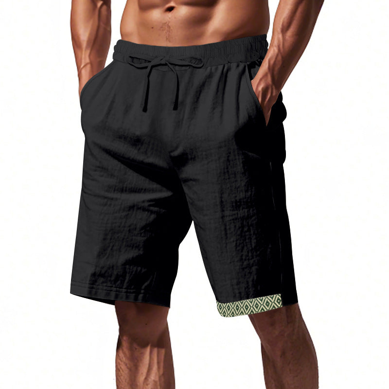 Pantaloncini uomo neri con elastico in vita e tasche, dettagli geometrici verdi sull'orlo. Ideali per sport e tempo libero.