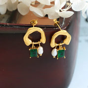 Orecchini pendenti in oro con perle e pietre verdi, design moderno. Accessori moda eleganti per donna. Gioielli di tendenza.