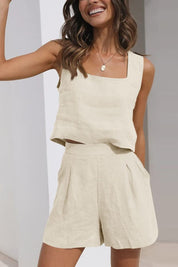 Donna sorridente in completo estivo beige, top senza maniche e pantaloncini a vita alta. Moda casual, abbigliamento leggero in lino.