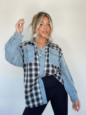 Donna con camicia a quadri bianca e nera, maniche in denim, posa su sfondo neutro. Moda casual, stile autunnale, abbigliamento femminile trendy.