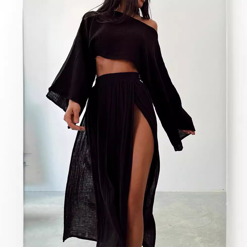Abito lungo nero elegante con spacco alto, manica lunga asimmetrica, stile moderno, perfetto per serate e occasioni speciali.