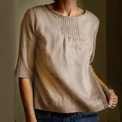 Blusa beige da donna in cotone, maniche a tre quarti, scollo rotondo, dettagli plissettati sul petto, stile casual elegante.