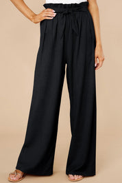 Pantaloni neri a vita alta con cintura, design ampio e pieghe, indossati da una modella. Ideali per look eleganti e casual.