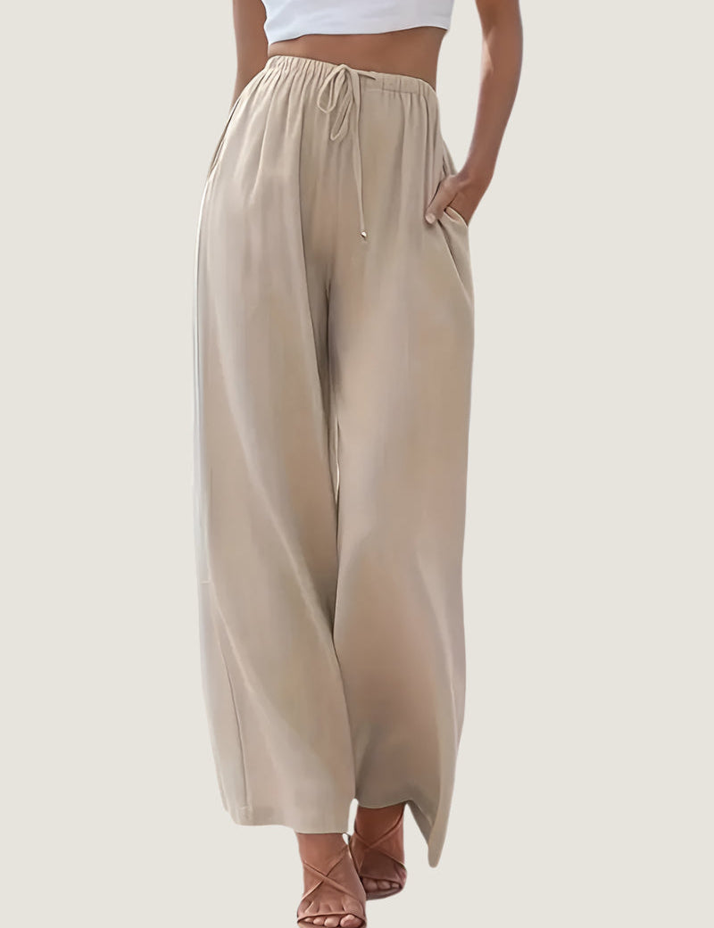 Pantaloni palazzo beige da donna, vita alta con coulisse, tessuto leggero, tasche laterali, abbinati a top bianco. Moda estiva casual elegante.