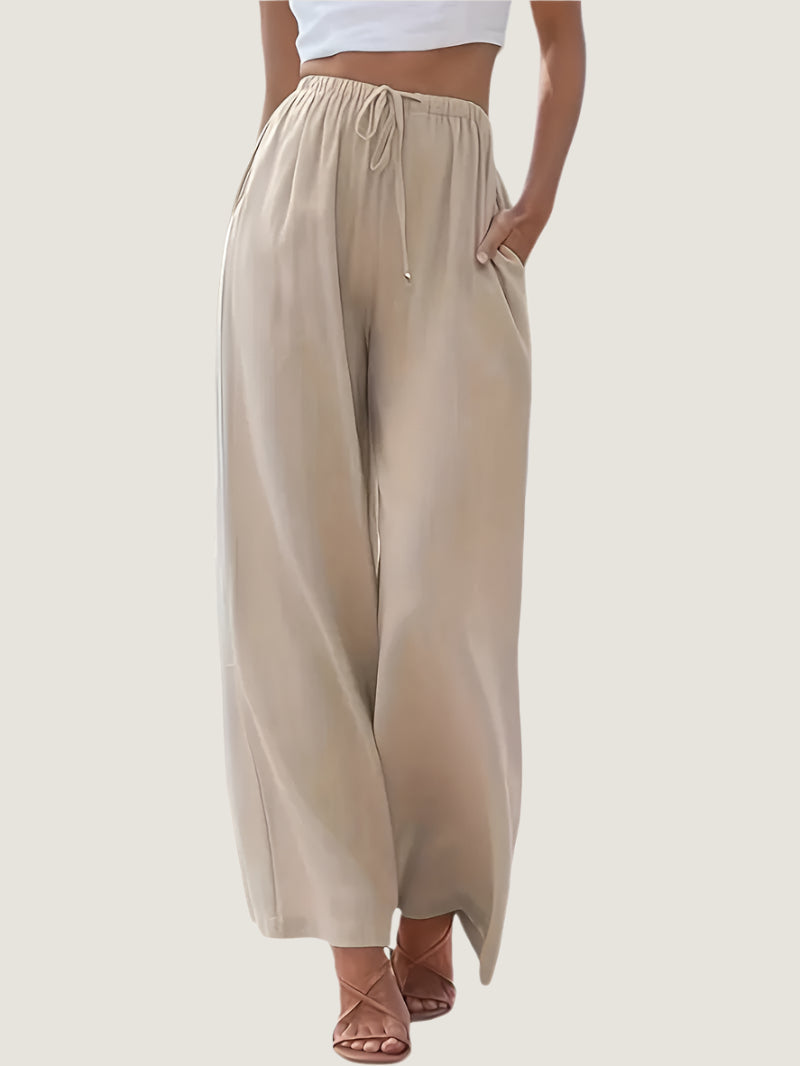 Pantaloni palazzo beige da donna, vita alta con coulisse, tessuto leggero, tasche laterali, abbinati a top bianco. Moda estiva casual elegante.