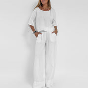 Donna in completo bianco estivo, maglia a maniche corte e pantaloni larghi. Moda casual elegante, abbigliamento leggero in lino.