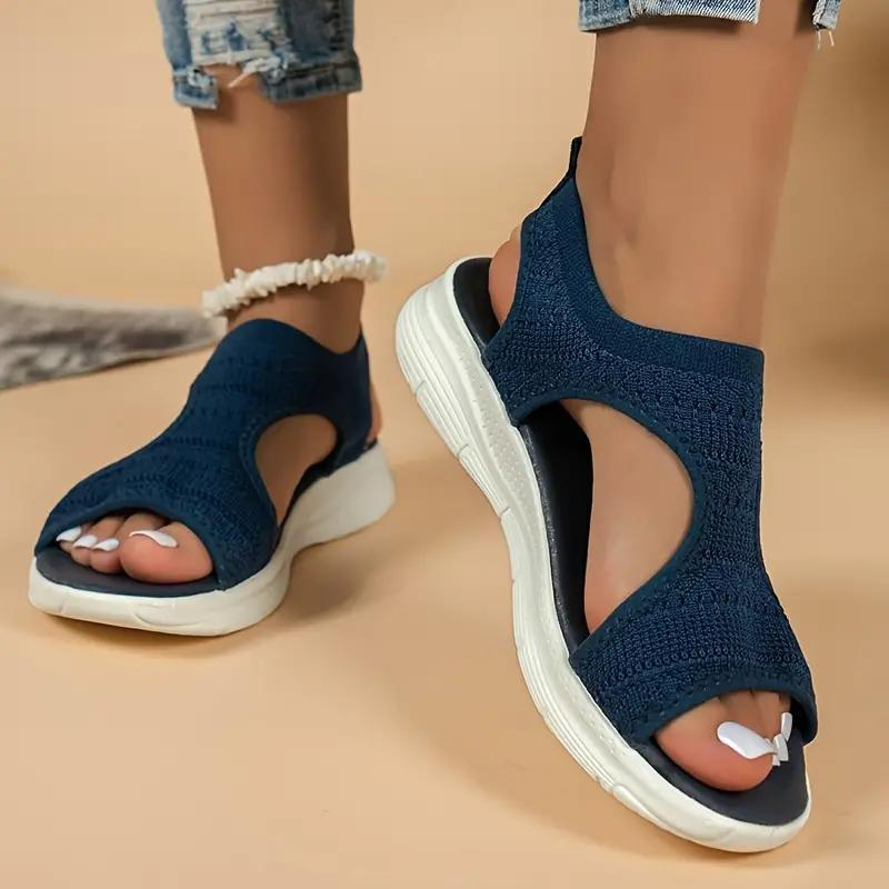 Sandali sportivi da donna blu scuro, suola bianca, design traforato, indossati con jeans strappati. Scarpe estive comode e alla moda.