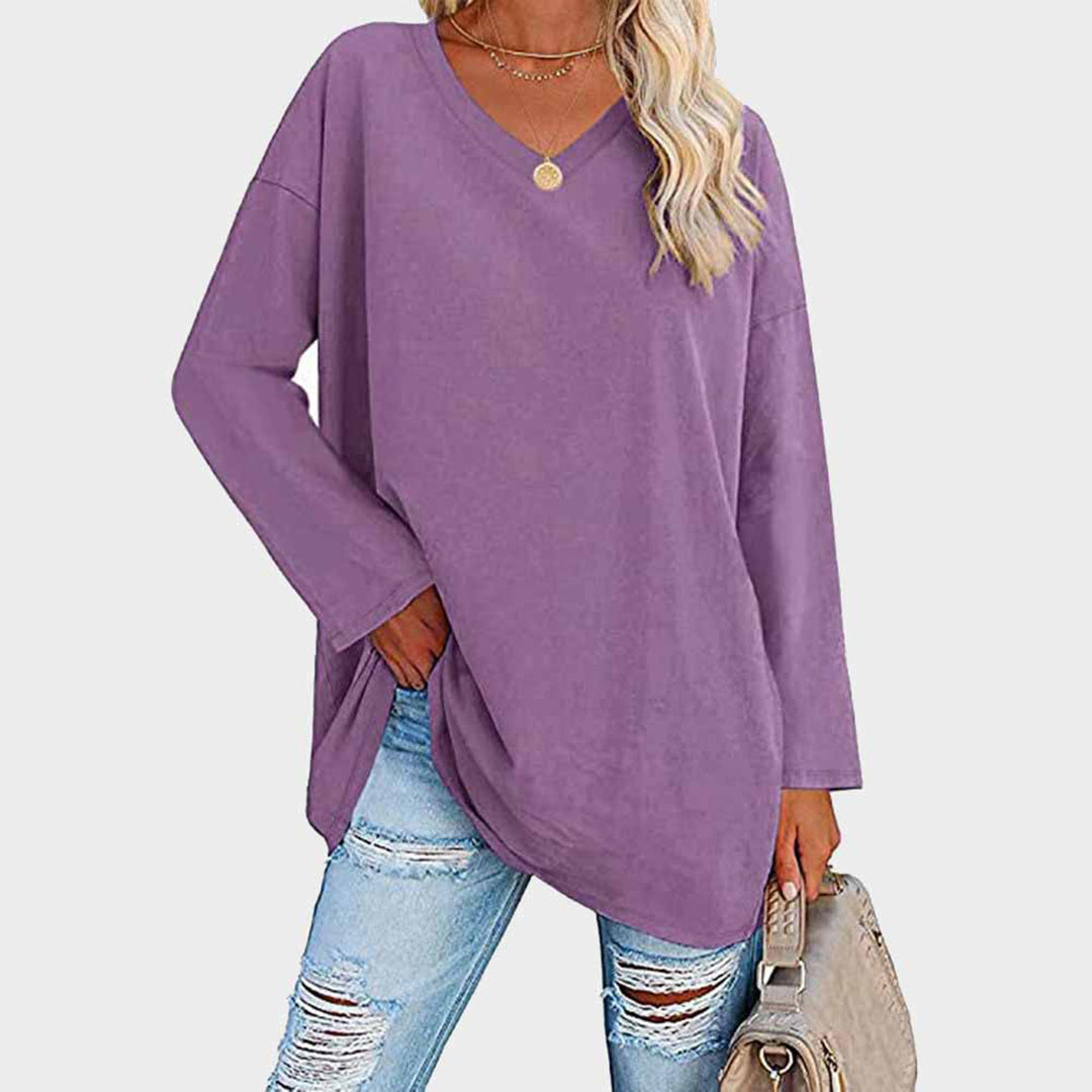 Maglia oversize viola donna, maniche lunghe, scollo a V, abbinata a jeans strappati. Look casual moda autunno.