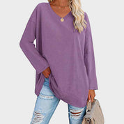 Maglia oversize viola donna, maniche lunghe, scollo a V, abbinata a jeans strappati. Look casual moda autunno.