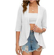 Giacca cardigan bianca traforata da donna, maniche a tre quarti, abbinata a top bianco e shorts di jeans strappati. Moda estiva casual.