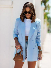 Donna con blazer azzurro, occhiali da sole, borsa marrone e shorts di jeans. Moda estiva elegante, look casual chic.