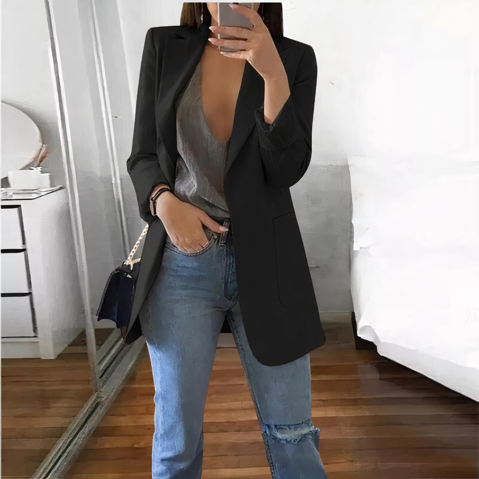 Donna in blazer nero e jeans strappati, specchio a figura intera, camera da letto moderna. Moda casual chic, outfit autunnale elegante.