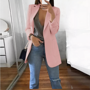Giacca rosa elegante su donna, abbinata a jeans casual e top grigio, in una stanza moderna con specchio. Moda femminile, abbigliamento casual chic.