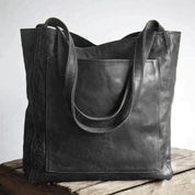 Borsa tote in pelle nera su tavolo di legno, design elegante e spazioso, ideale per moda donna, accessori di lusso, shopping e lavoro.
