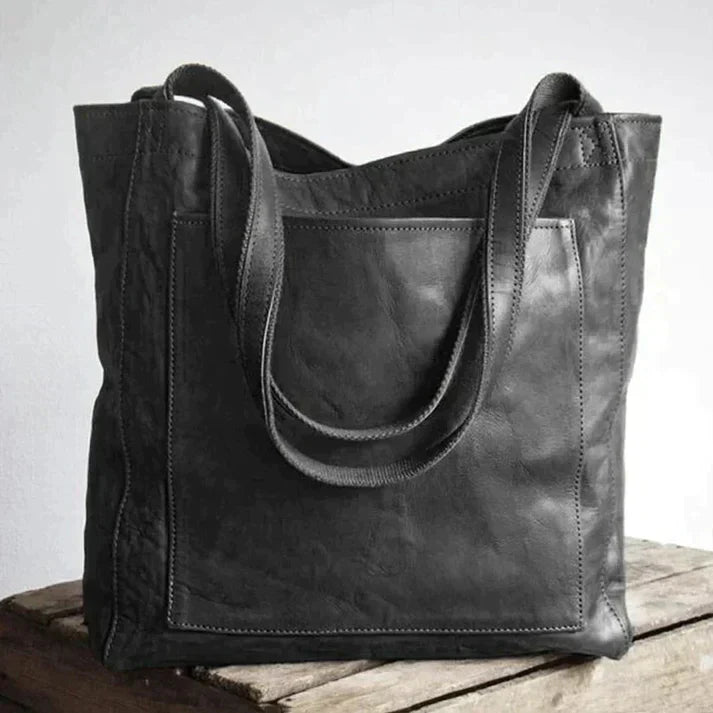 Borsa tote in pelle nera su tavolo di legno, design elegante e spazioso, ideale per moda donna, accessori di lusso, shopping e lavoro.