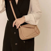 Borsa a tracolla beige in pelle, design moderno, indossata su abito nero e bianco. Accessorio moda donna elegante e versatile.