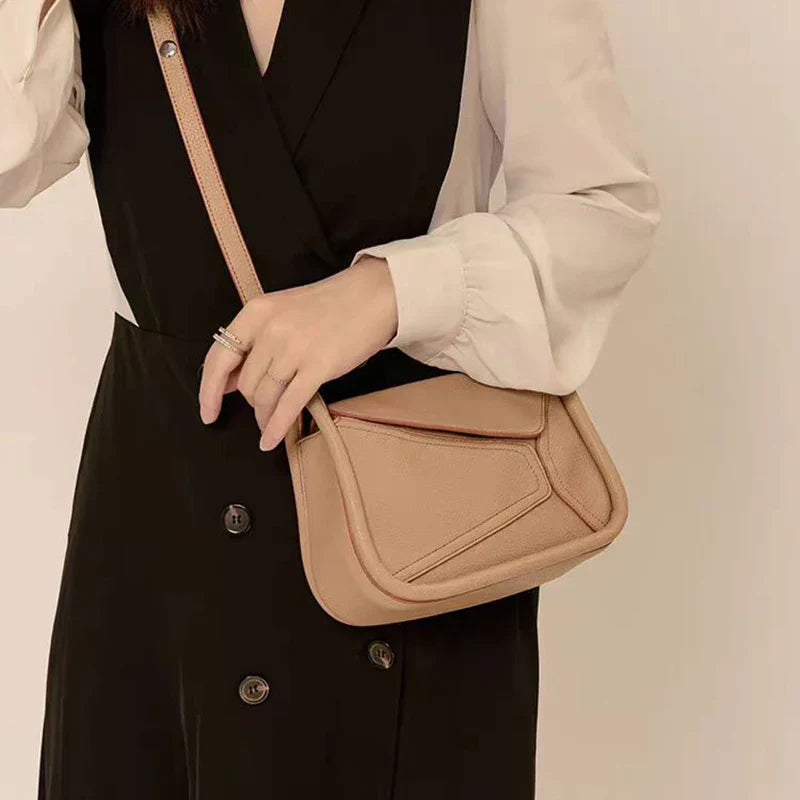 Borsa a tracolla beige in pelle, design moderno, indossata su abito nero e bianco. Accessorio moda donna elegante e versatile.