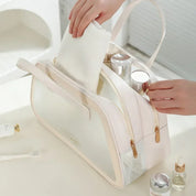 Borsa da toilette trasparente con cerniera, contenente flaconi cosmetici e asciugamano bianco. Ideale per viaggi, organizzazione prodotti bellezza.