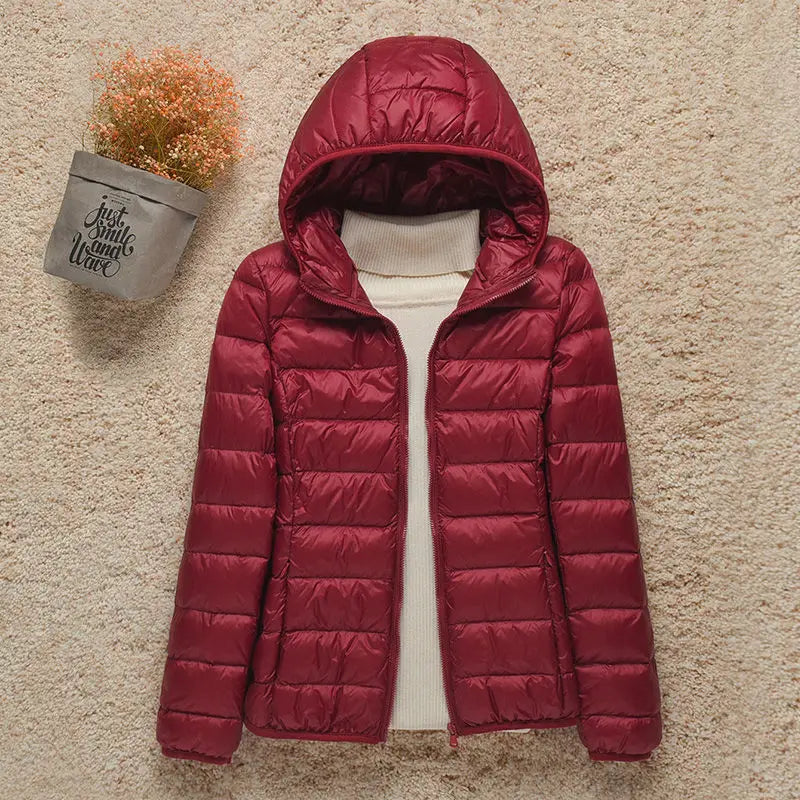 Giacca invernale donna rossa con cappuccio, imbottita, su sfondo beige. Moda calda e casual, perfetta per l'autunno e l'inverno.