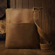 Borsa a tracolla in pelle marrone, design elegante e minimalista, ideale per uomo e donna. Accessorio moda resistente e versatile.