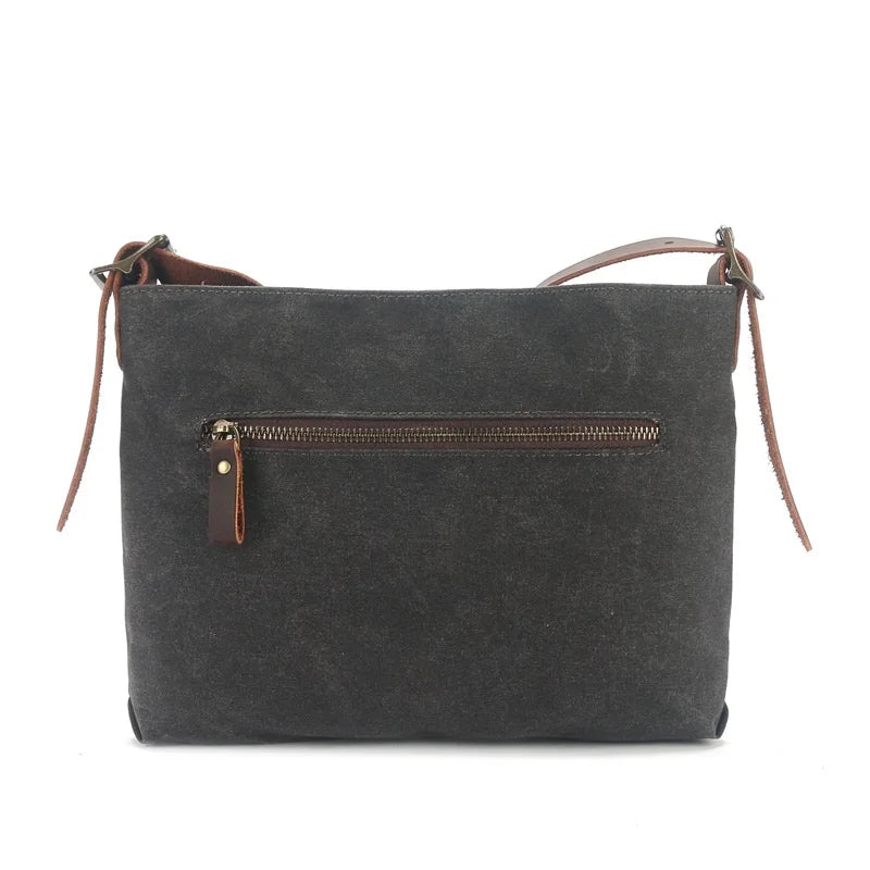 Borsa a tracolla in tela nera con cerniera frontale, design minimalista, dettagli in pelle marrone, ideale per uso quotidiano e casual.