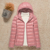 Giacca invernale rosa con cappuccio, imbottita, su sfondo beige. Perfetta per moda donna, abbigliamento caldo e casual.