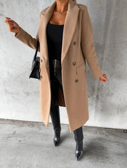 Cappotto lungo beige elegante, doppio petto, indossato con top nero, pantaloni in pelle e stivali. Look autunnale chic e moderno.