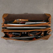 Borsa in pelle marrone aperta, vista dall'alto, con scomparti organizzati per laptop, documenti e accessori. Elegante e funzionale per lavoro.