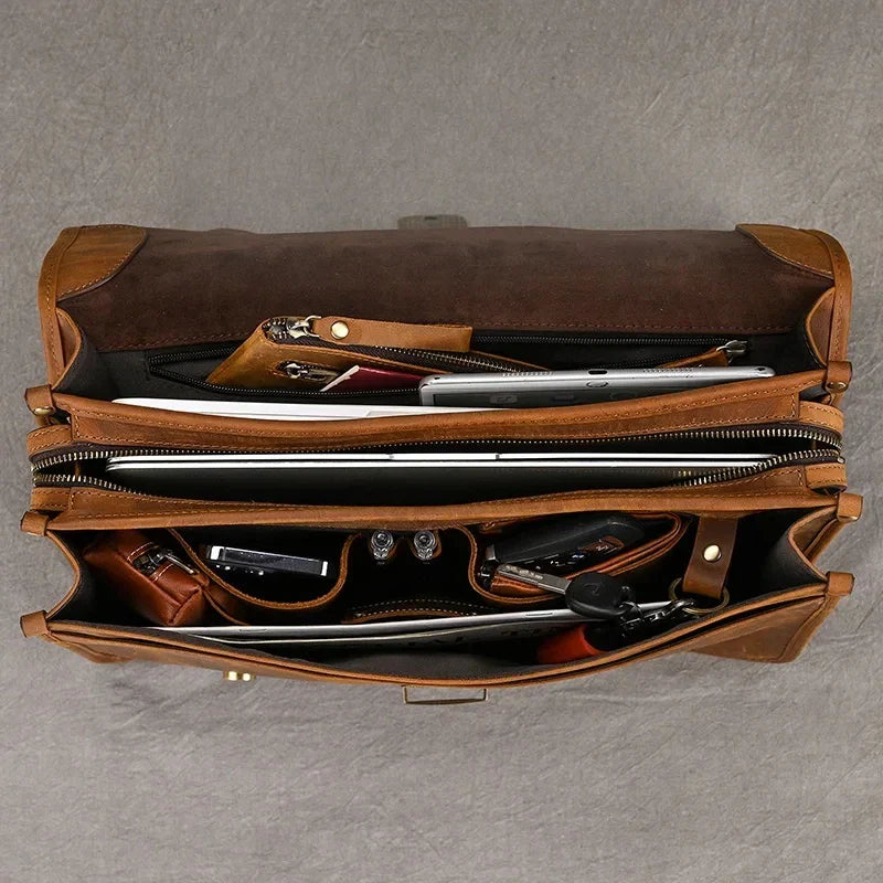 Borsa in pelle marrone aperta, vista dall'alto, con scomparti organizzati per laptop, documenti e accessori. Elegante e funzionale per lavoro.
