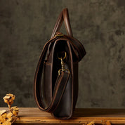 Borsa a tracolla in pelle marrone scuro, design elegante e vintage, con dettagli in metallo dorato, ideale per lavoro e viaggi.