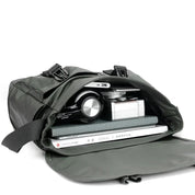 Borsa a tracolla verde aperta con fotocamera, libri e laptop all'interno. Design moderno, ideale per viaggi e lavoro. Accessori organizzati.