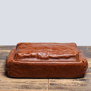 Borsa a tracolla in pelle marrone vintage su tavolo in legno, design elegante e resistente, ideale per uomo e donna, accessorio moda di alta qualità.