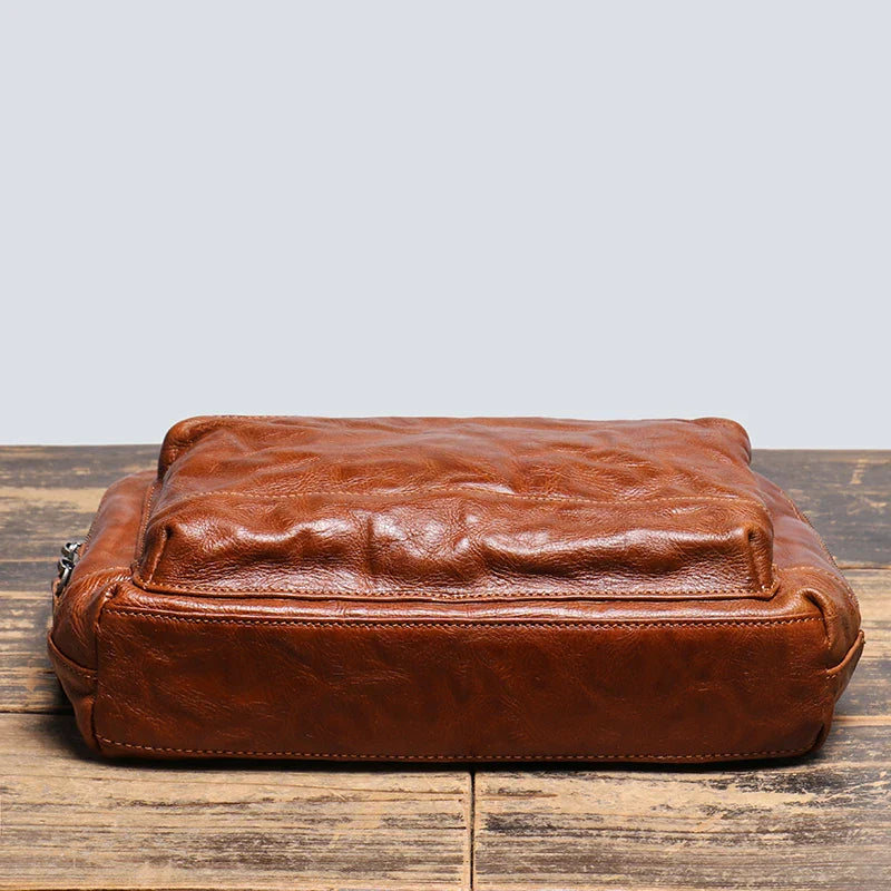 Borsa a tracolla in pelle marrone vintage su tavolo in legno, design elegante e resistente, ideale per uomo e donna, accessorio moda di alta qualità.