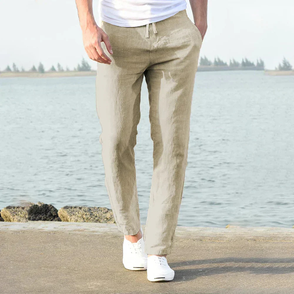 Pantaloni uomo in lino beige, stile casual, con coulisse, indossati vicino al mare. Ideali per look estivo, comodi e traspiranti.