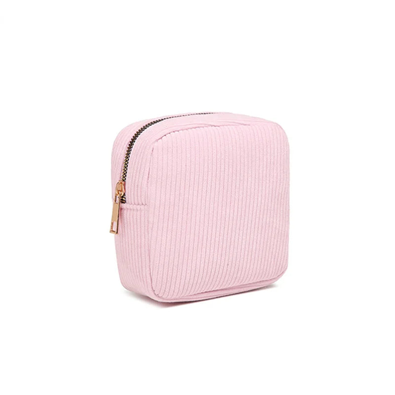 Astuccio quadrato rosa in tessuto a coste con cerniera dorata, ideale per cosmetici o accessori. Design elegante e pratico per l'uso quotidiano.